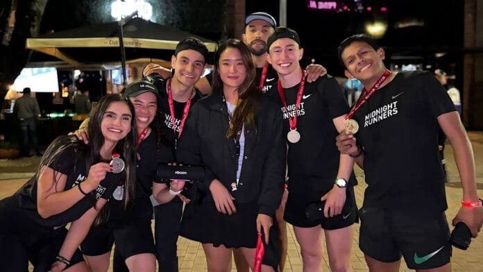 Grupo completo de corredores Midnight Runners celebrando alianza con LG en evento de running urbano nocturno en Bogotá