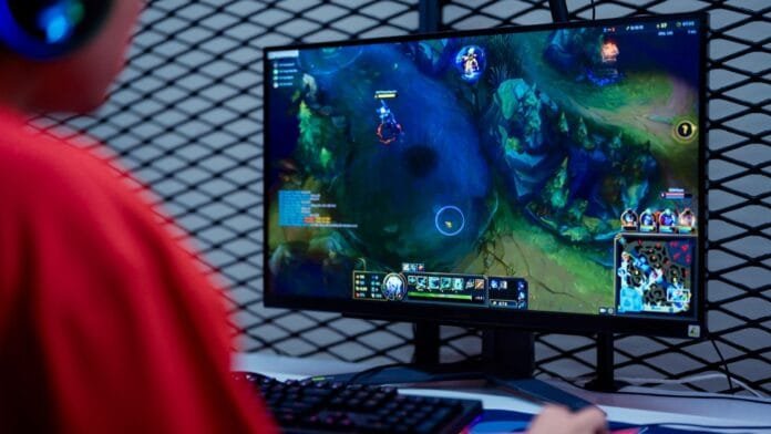 monitor-gaming-setup-league-of-legends-2025 Setup gaming con monitor mostrando League of Legends en ambiente con iluminación RGB controlada, ideal para gaming competitivo