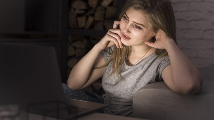 mujer-fatiga-visual-pantalla-laptop-noche-luz-azul Mujer joven con fatiga visual usando laptop en la noche, mostrando síntomas de exposición prolongada a luz azul de pantallas