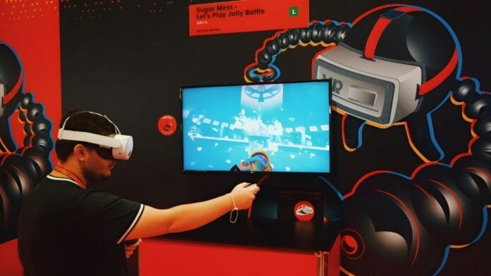 Desarrollador usando visor VR en stand de gamescom latam BIG Festival con pantalla mostrando juego indie