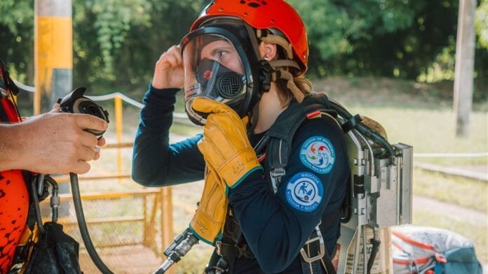 Mujer brigadista en entrenamiento de gestión de emergencias con equipo SCBA y rescate industrial