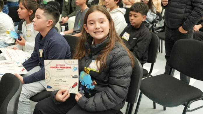 Niña ganadora del Toyota Dream Car sostiene su certificado de reconocimiento
